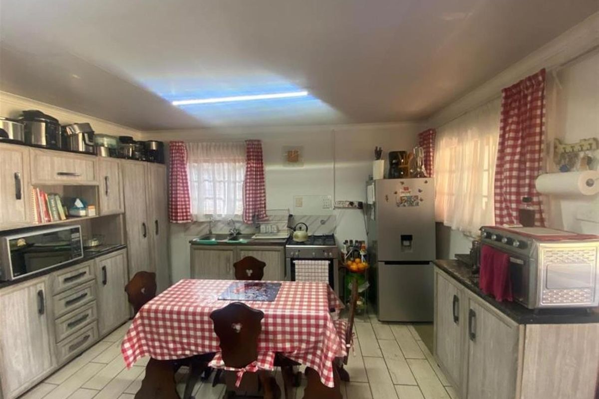 A functional kitchen featuring built-in cabinetry, a double sink, and a gas stove, with tiled flooring throughout.
