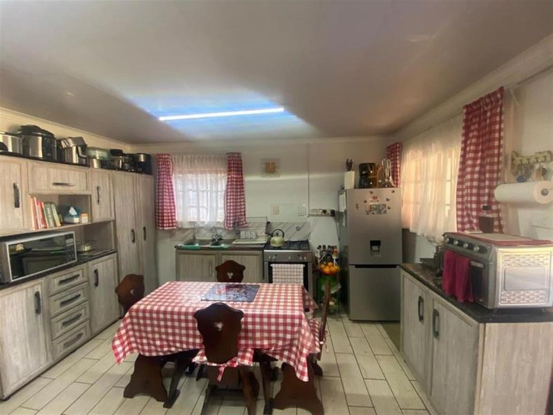 A functional kitchen featuring built-in cabinetry, a double sink, and a gas stove, with tiled flooring throughout.