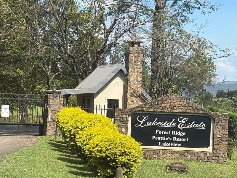Entrance to Lakeside Estate featuring a stone masonry gatehouse, security gate, and prominent estate signage set within a landscaped garden.