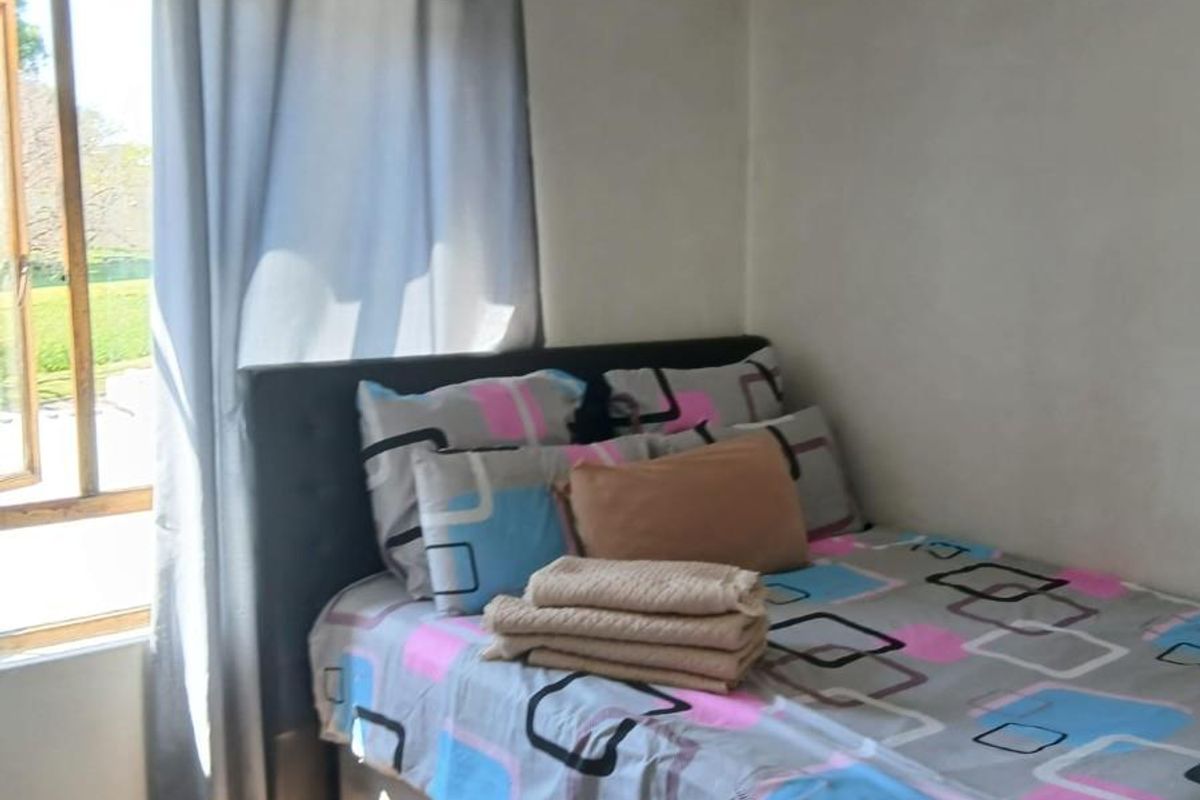A bedroom featuring a window with natural light, carpeted flooring, and plain wall finishes.