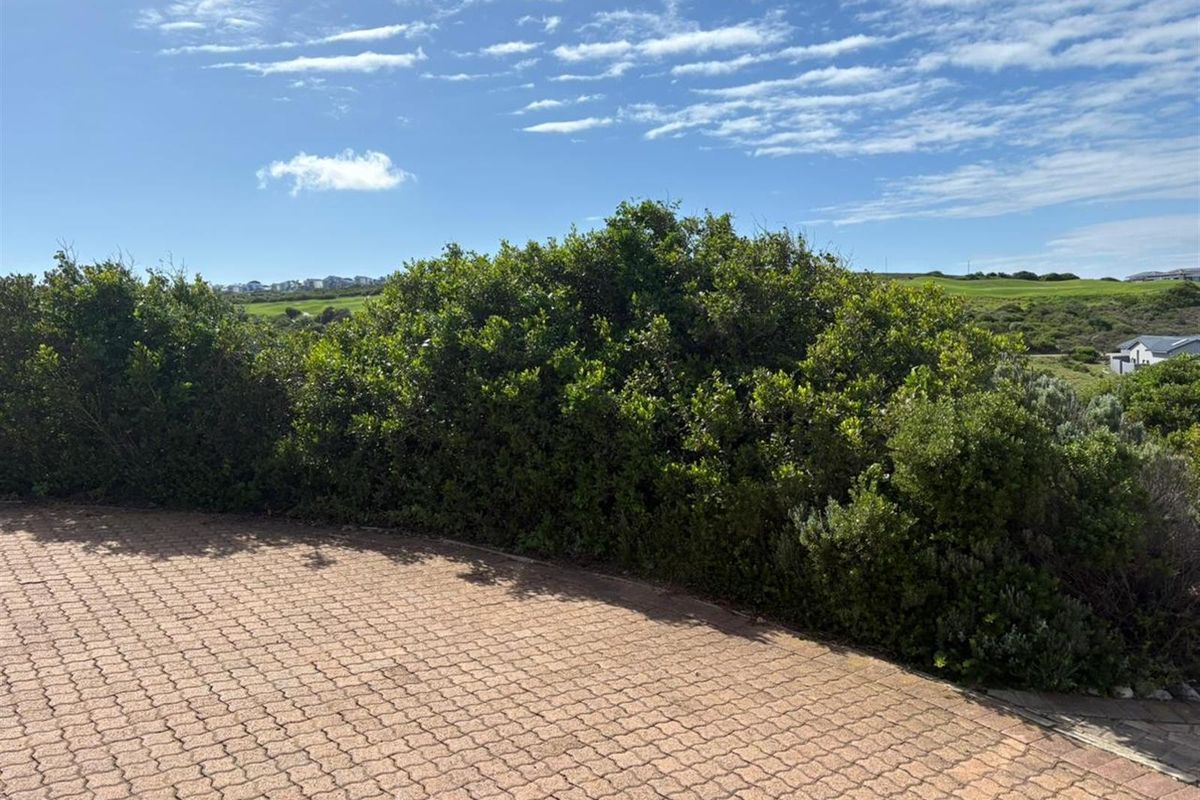 A view of the residential land featuring established shrubbery and a paved driveway area with surrounding landscape views.