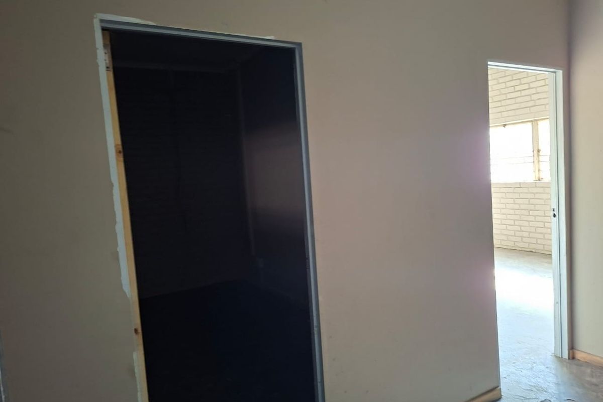 An interior view of a commercial space featuring unfinished door frames and exposed brickwork, showing potential for renovation and layout customization.