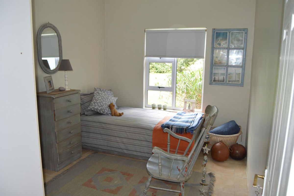 A compact bedroom featuring tiled flooring and a single window with a roller blind, offering a functional and neutral living space.