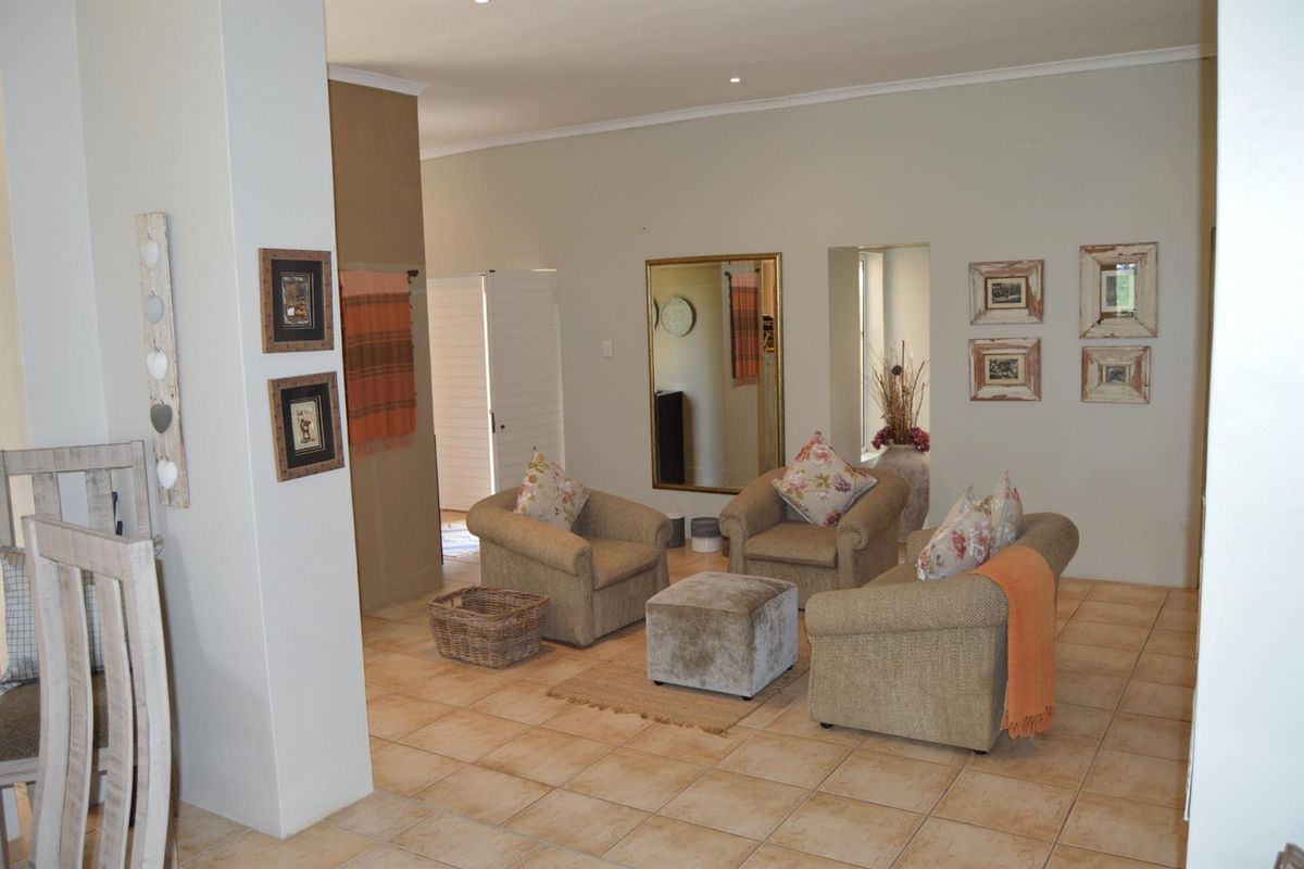 A spacious living area featuring neutral wall tones, tiled flooring, and recessed lighting, offering a comfortable and versatile space for relaxation.