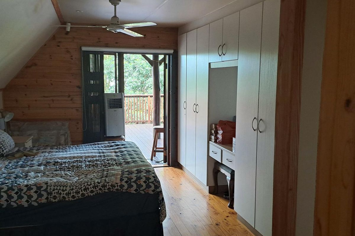 A bedroom featuring timber wall cladding, polished timber floors, extensive built-in cabinetry, and direct access to an outdoor balcony through sliding glass doors.