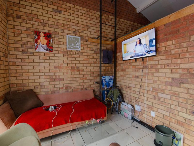 A living room featuring exposed face brick walls, tiled flooring, and a high ceiling with a vertical metal ladder structure.