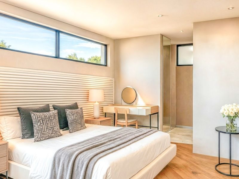 Modern bedroom featuring a horizontal slat feature wall, clerestory windows for natural light, hardwood flooring, and an integrated en-suite bathroom.