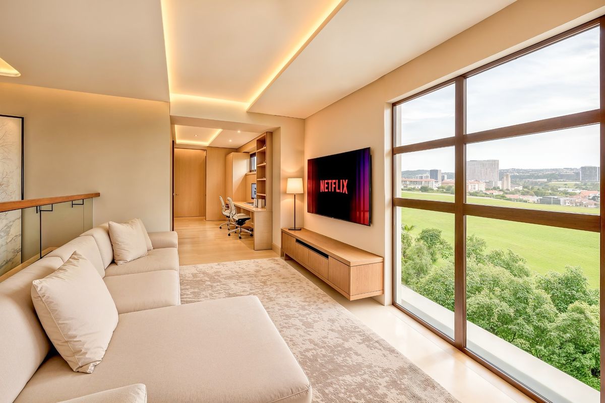 Modern living room featuring recessed ceiling lighting, built-in cabinetry, and large windows offering expansive views, seamlessly connected to a dedicated home office space.