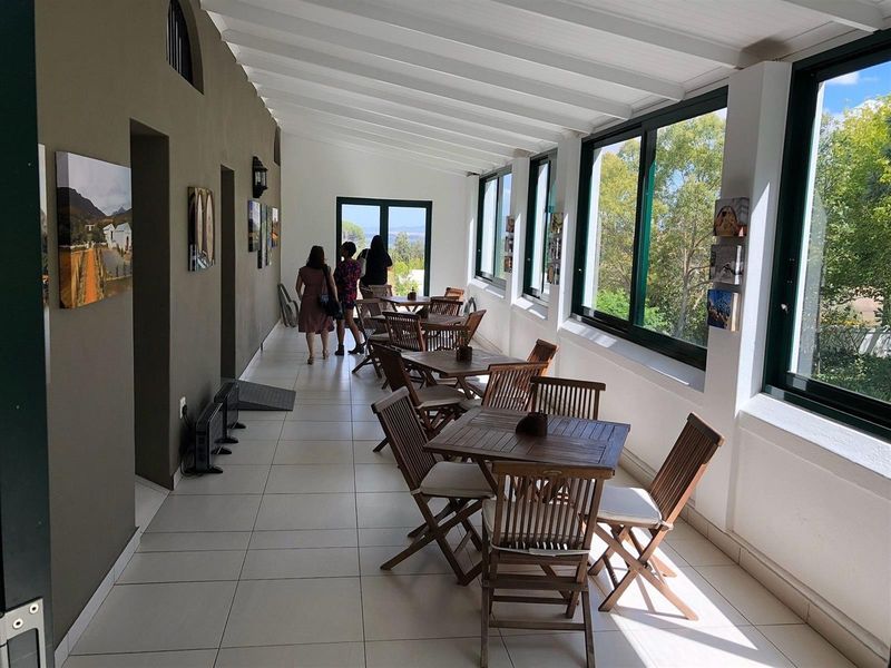 A bright, enclosed patio area featuring tiled flooring, exposed beam ceilings, and large windows offering scenic views, suitable for dining or relaxation.