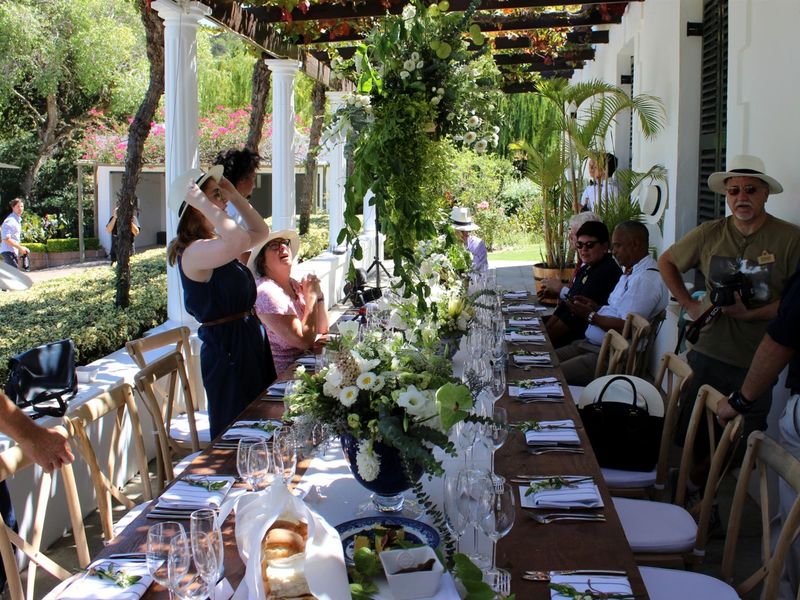 A covered outdoor patio area featuring a pergola structure and classic columns, overlooking a lush garden setting.