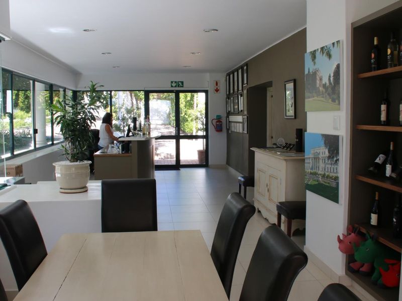 A bright and welcoming reception area featuring tiled flooring, built-in display shelving, and a functional service desk with direct access to the exterior.