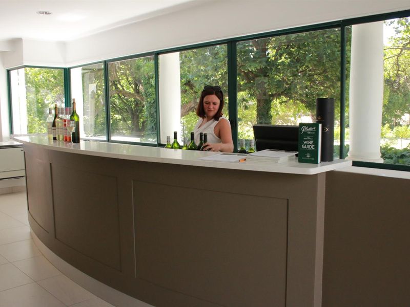 A well-maintained bar area featuring a curved built-in counter, large windows overlooking the garden, and clean tiled flooring.