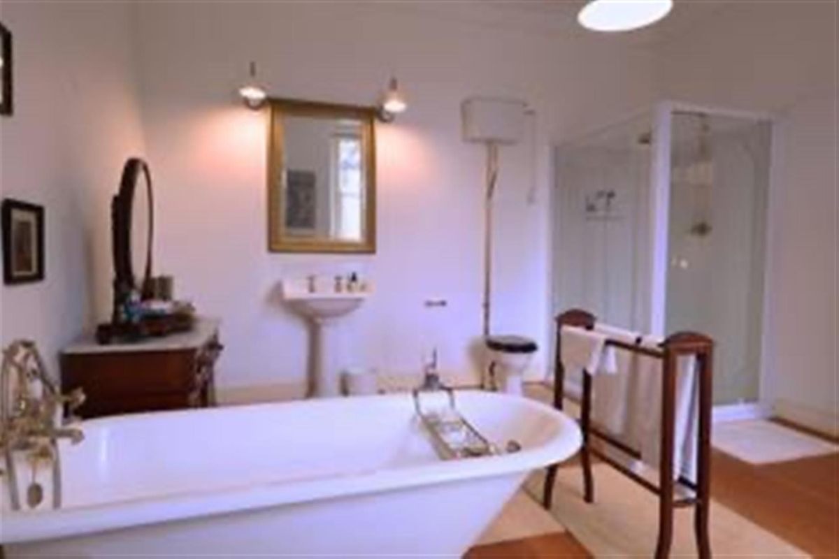 A traditional-style bathroom featuring a freestanding bathtub, pedestal basin, high-level cistern toilet, and a separate glass-enclosed shower unit.