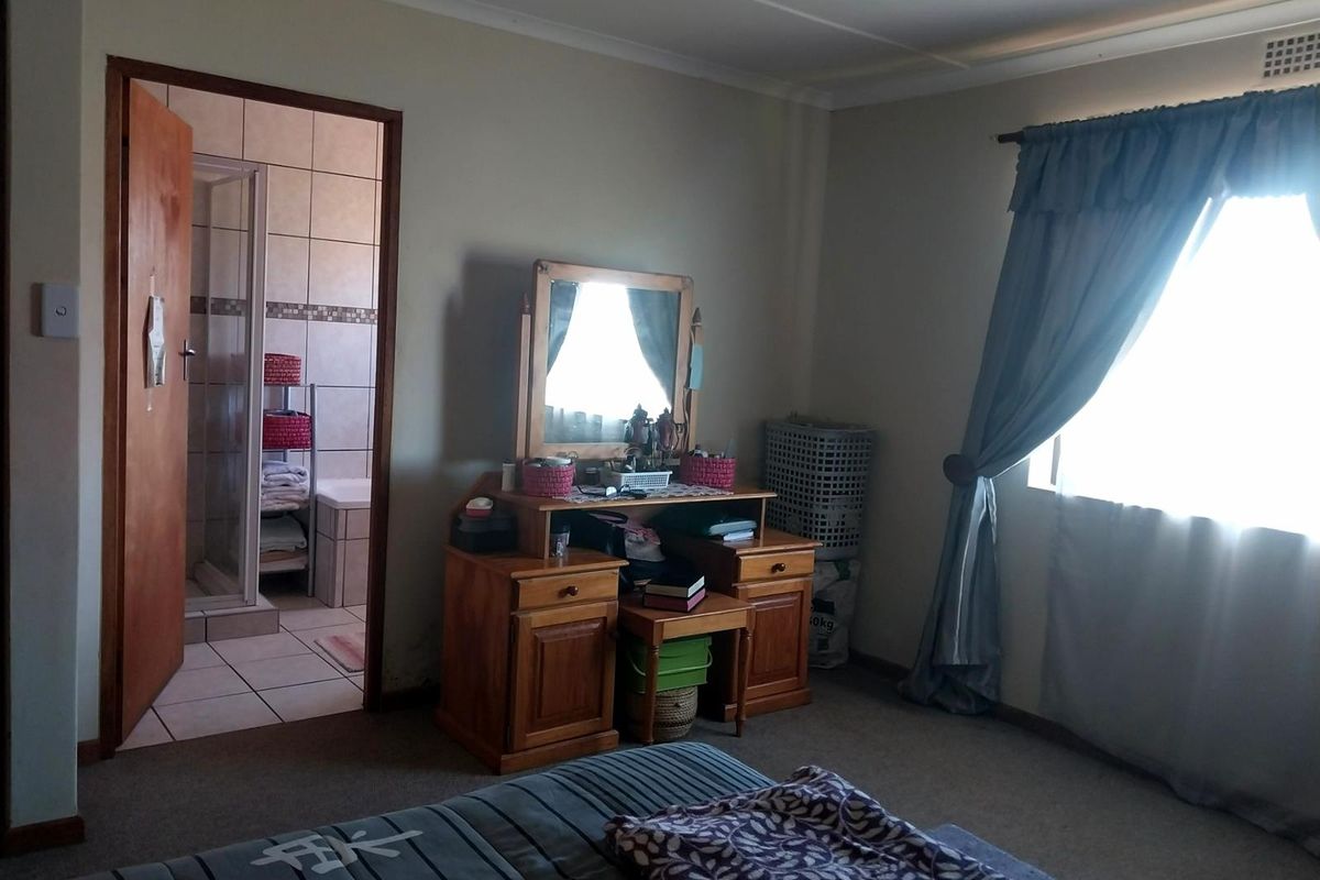 A bedroom featuring carpeted flooring and an en-suite bathroom with tiled finishes and a shower enclosure.