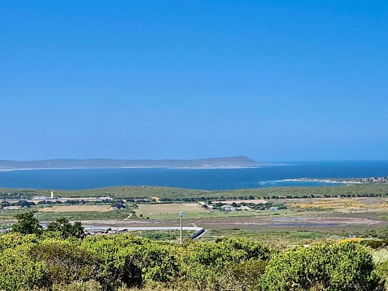 A scenic elevated view overlooking the coastal landscape, natural vegetation, and the ocean in the distance.