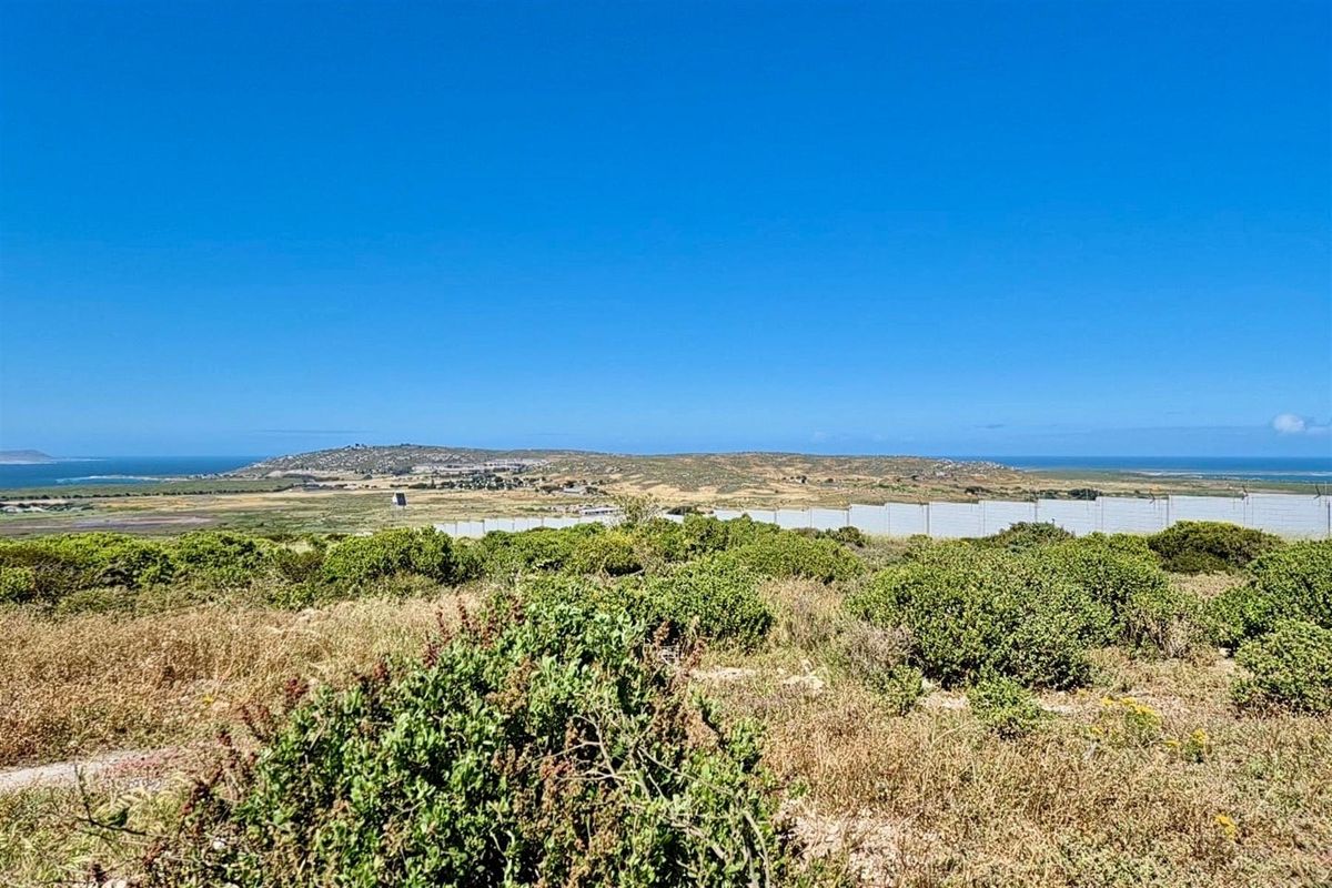 A wide-angle view of the vacant residential land, showcasing the surrounding landscape, natural vegetation, and distant coastal horizon.