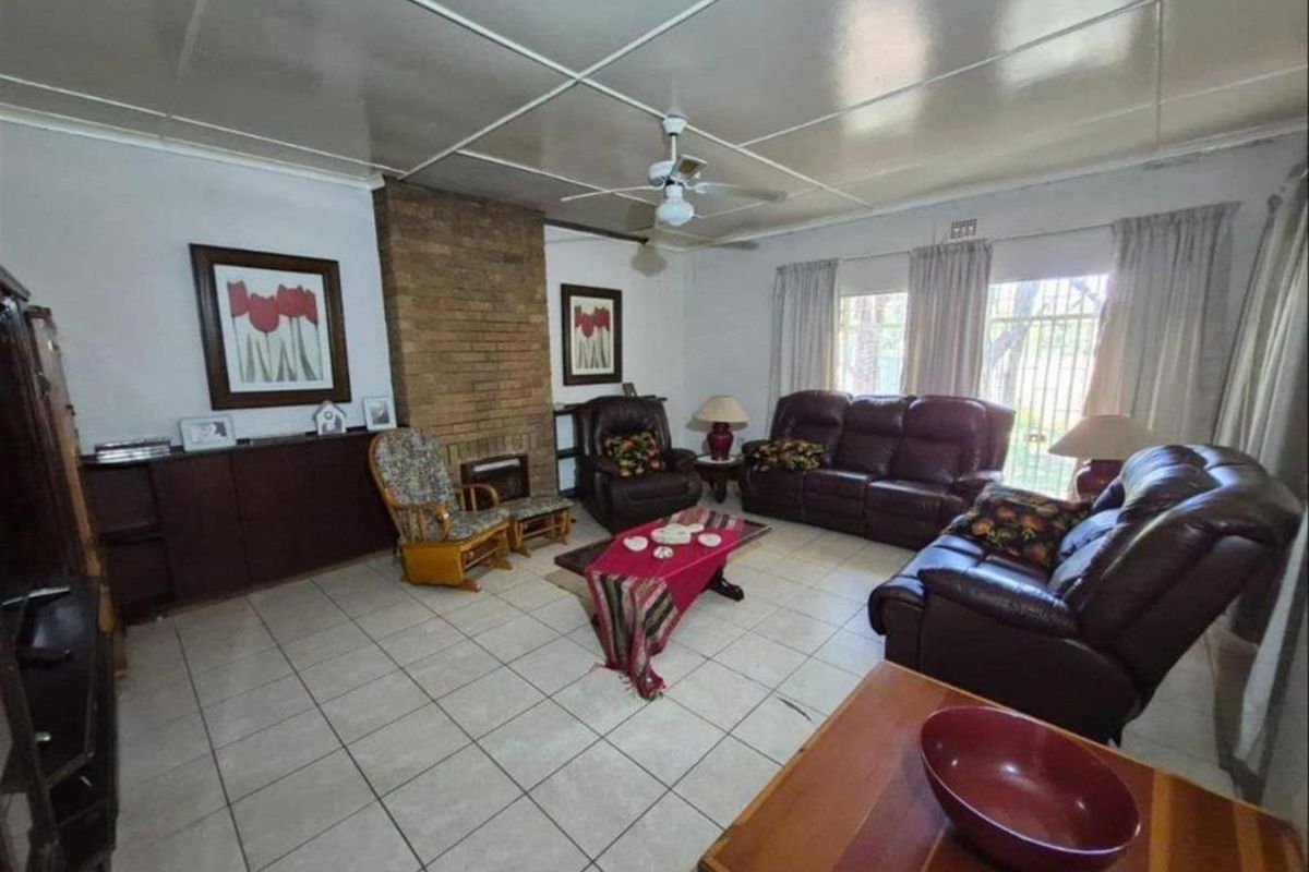 Spacious living room featuring a brick fireplace, tiled flooring, and a ceiling fan, offering a comfortable and functional living space.
