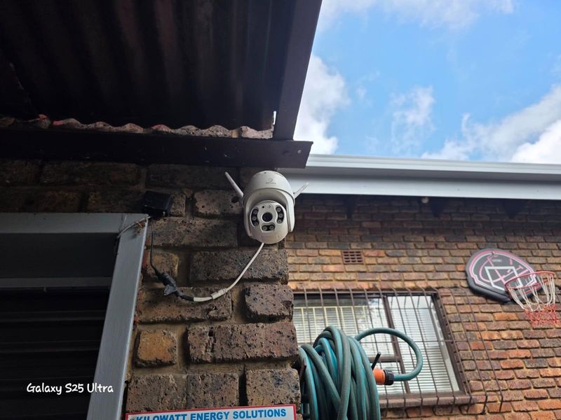 Exterior view of a brick wall featuring a mounted security camera and protective window burglar bars.