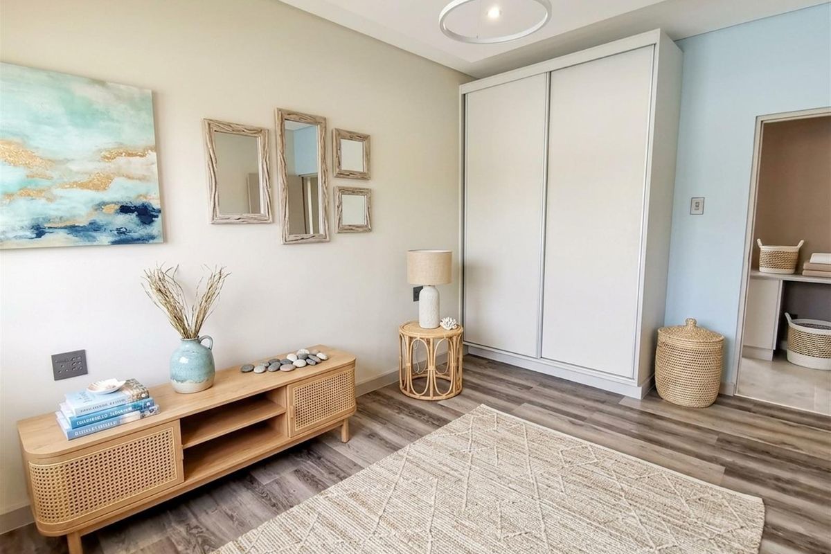 A well-maintained bedroom featuring modern wood-look flooring, a built-in sliding door wardrobe, and a neutral color palette.