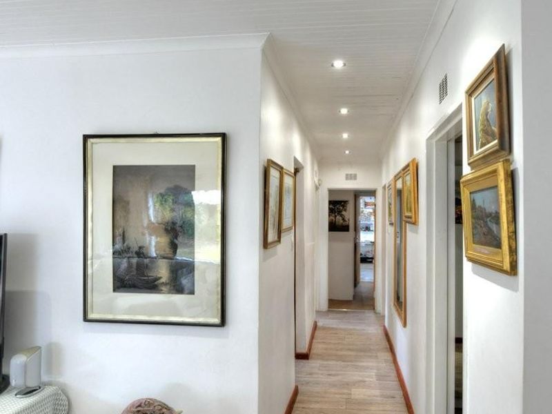 A bright, well-maintained hallway featuring wood-look flooring, recessed ceiling lighting, and a clean, neutral aesthetic connecting the living area to other rooms.