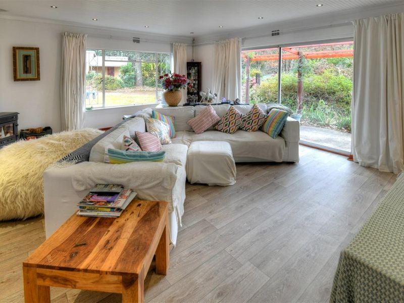 Spacious living room featuring light wood-look flooring, a built-in wood-burning fireplace, and large sliding glass doors providing access to the garden.