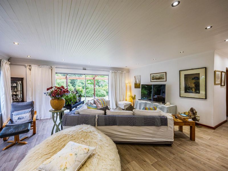 Spacious living room featuring wood-look flooring, recessed downlighting, and large sliding glass doors providing direct access to the rear garden and patio area.