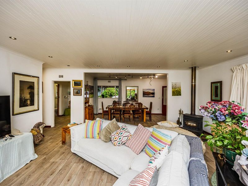 Open-plan living and dining area featuring wood-look flooring, recessed ceiling lighting, and a built-in wood-burning fireplace.