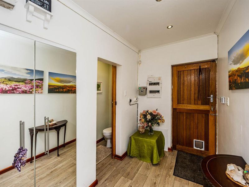 An entry hallway featuring wood-look flooring, a solid timber door with a pet flap, and access to an adjacent bathroom.