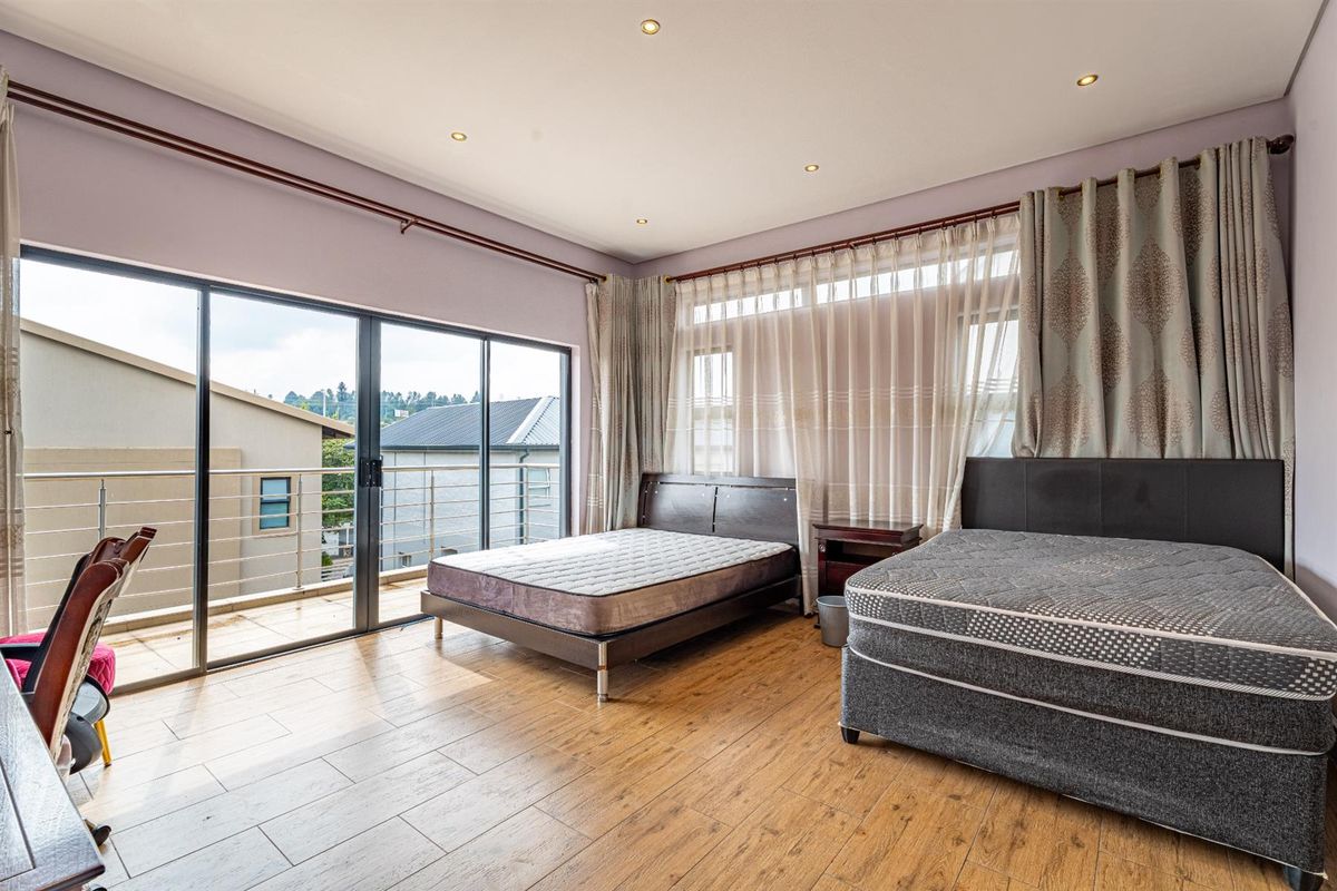 Spacious bedroom featuring wood-look tile flooring, recessed downlights, and large sliding glass doors opening onto a private balcony.