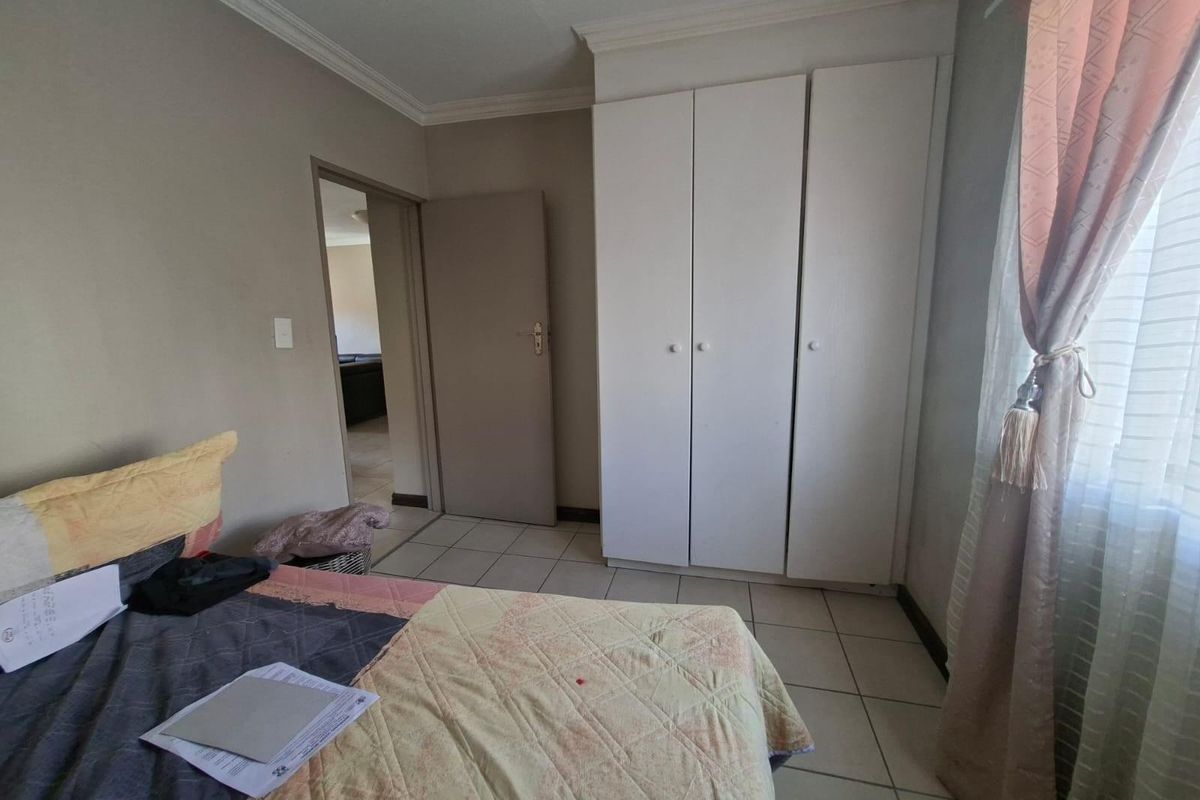 A bedroom featuring built-in white cabinetry, tiled flooring, and a doorway leading to an adjacent living area.