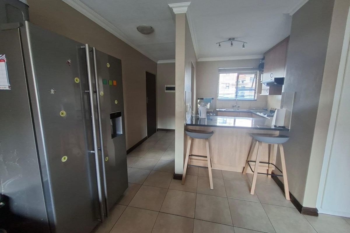 A functional kitchen featuring light wood cabinetry, dark countertops, a breakfast bar, and tiled flooring, providing a practical layout for daily meal preparation.
