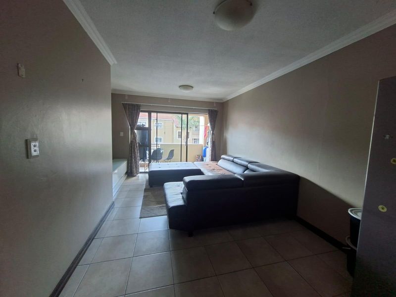 A living room featuring tiled flooring, crown molding, and sliding glass doors leading to an outdoor balcony area.