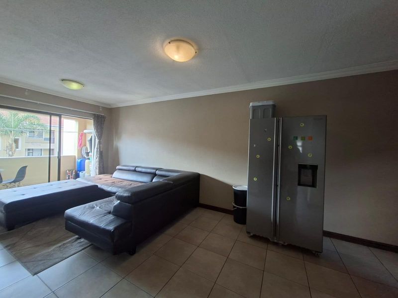 Open plan living area featuring tiled flooring, ceiling mounted lighting, and sliding glass doors providing access to an attached balcony.