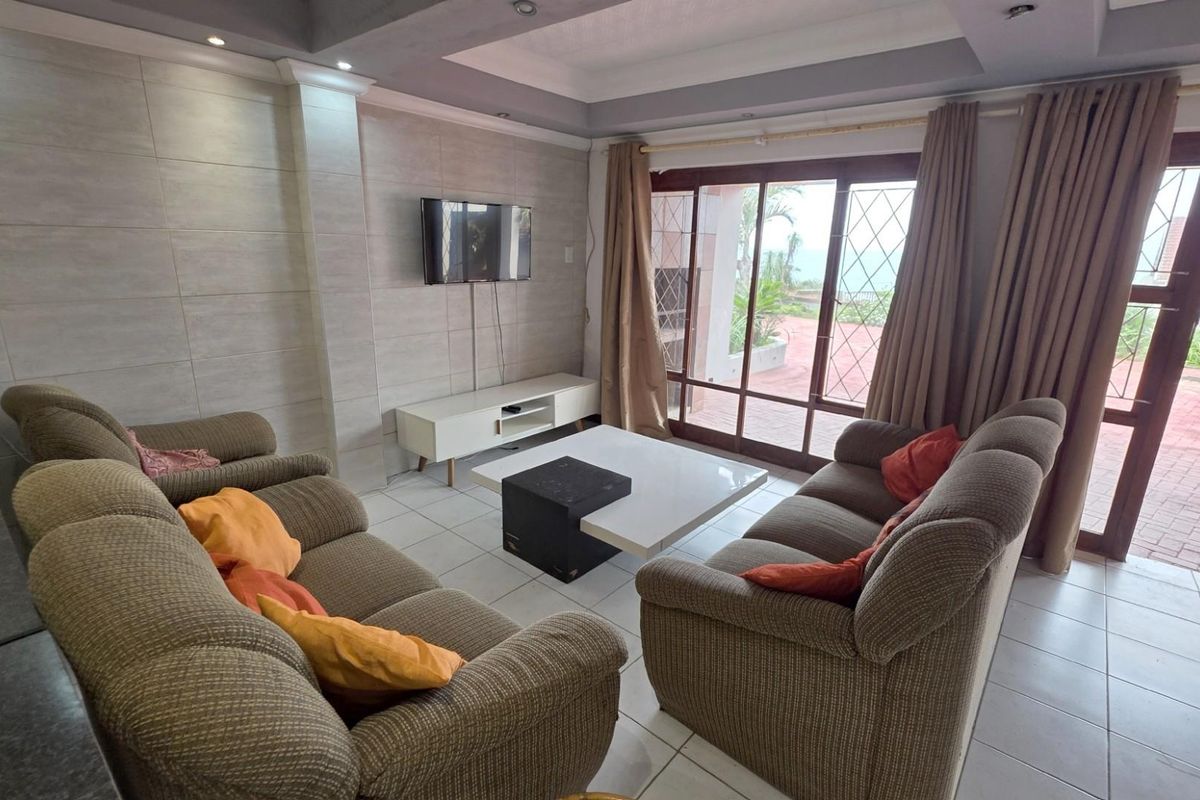Spacious living room featuring tiled flooring, recessed ceiling lighting, and large sliding glass doors providing direct access to the outdoor patio area.