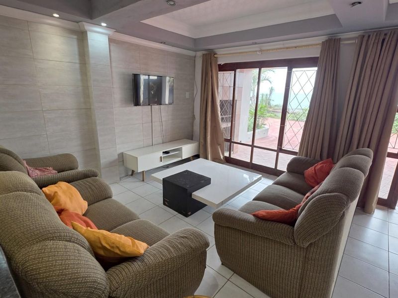 Spacious living room featuring tiled flooring, recessed ceiling lighting, and large sliding glass doors providing direct access to the outdoor patio area.