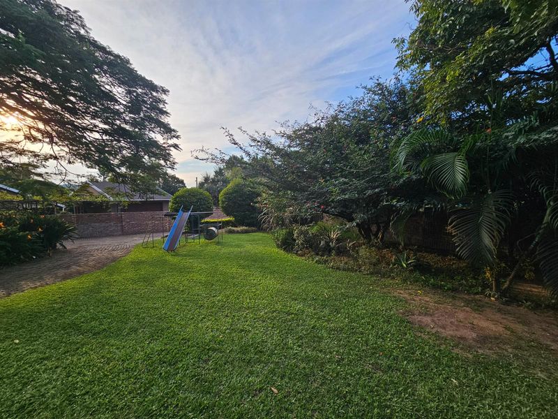 A spacious, well-maintained private garden featuring a lush green lawn, mature trees, and established landscaping, providing a peaceful outdoor setting.