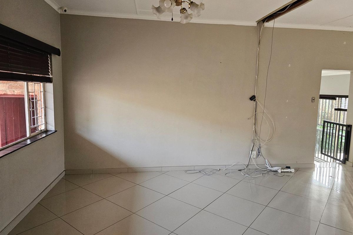 An empty living area featuring tiled flooring, a ceiling light fixture, and visible exposed wiring requiring maintenance or repair.