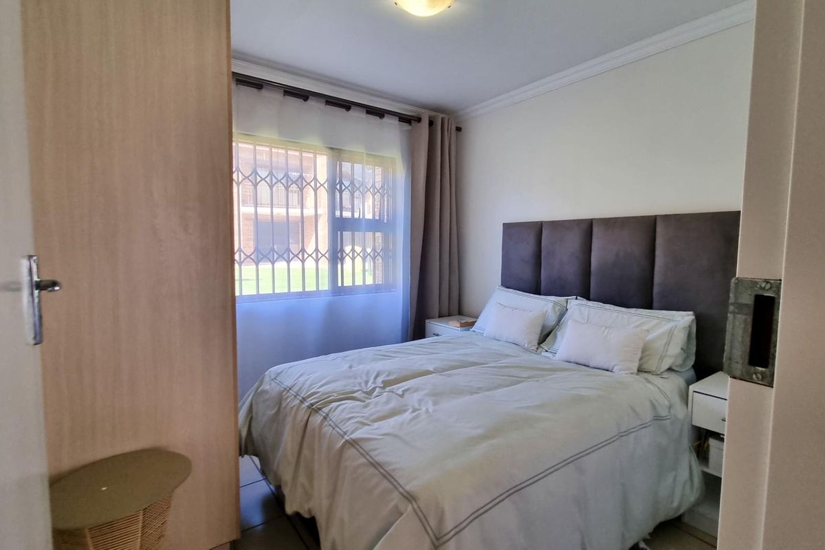 A cozy bedroom featuring built-in wooden cabinetry and a window fitted with security bars, providing natural light and functional storage space.