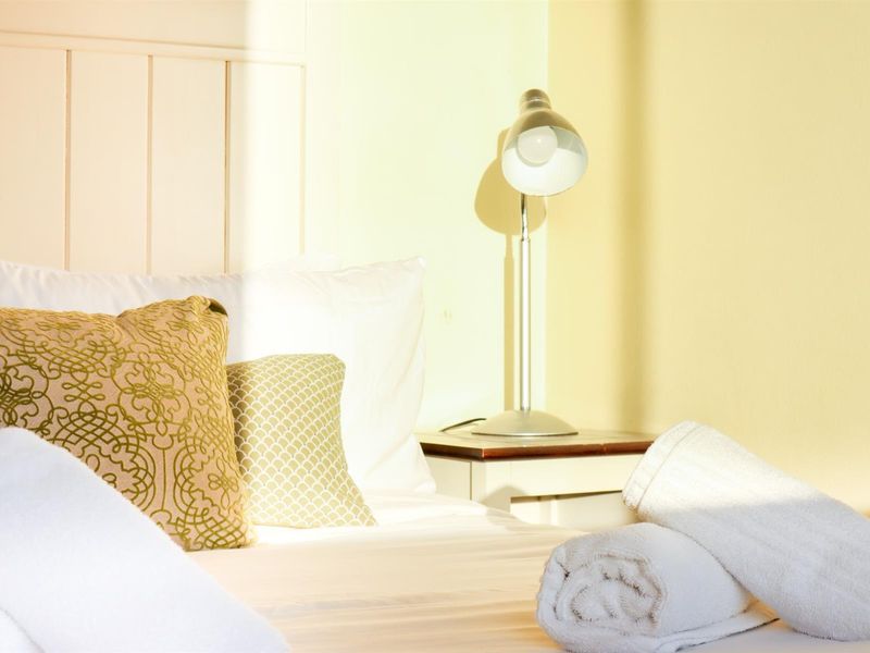 A close-up view of a bedroom featuring a white headboard and warm natural lighting.