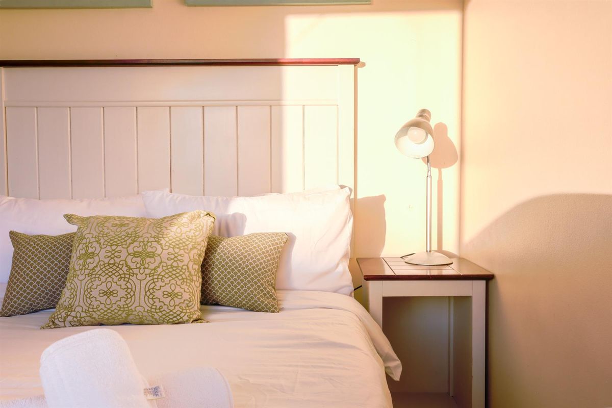 A cozy bedroom corner featuring a white panelled headboard and warm natural lighting.