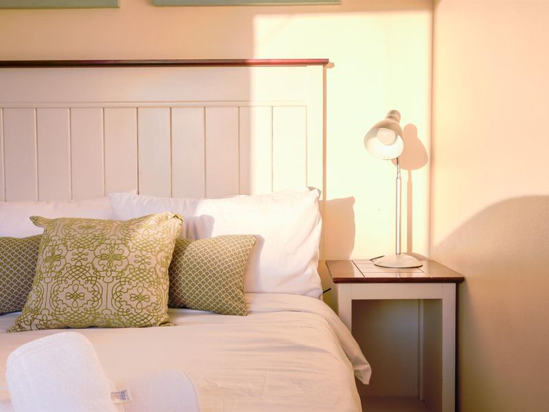 A cozy bedroom corner featuring a white panelled headboard and warm natural lighting.