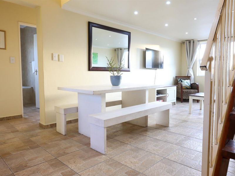 Open-plan living and dining area featuring tiled flooring, recessed downlighting, and a staircase, providing a functional and versatile living space.