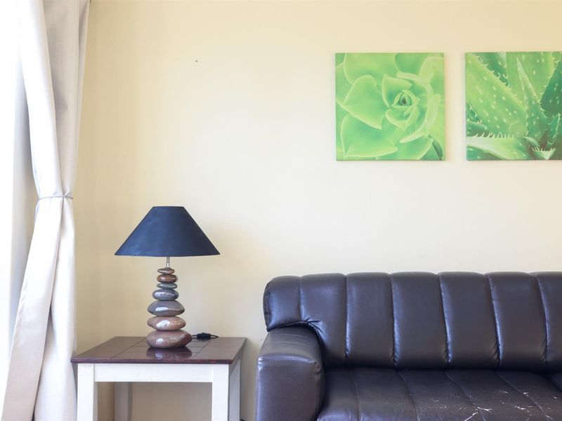 A view of a living room area featuring neutral wall finishes and natural light from an adjacent window.