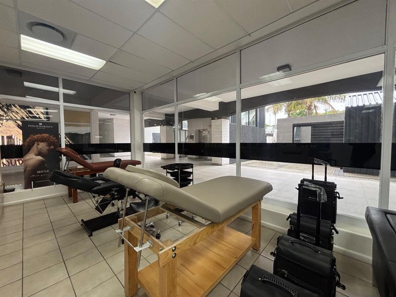 A bright commercial office or treatment space featuring large glass windows, tiled flooring, and a suspended ceiling, suitable for professional or retail use.