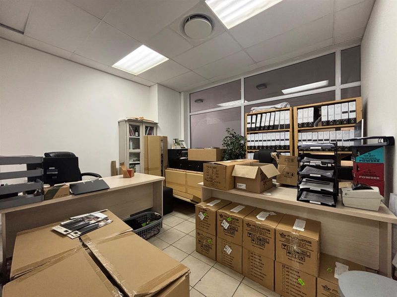 A functional commercial office space featuring tiled flooring, suspended ceilings with recessed lighting, and integrated glass partitioning.