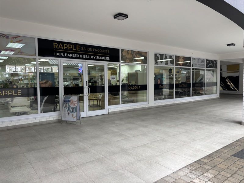 Commercial storefront featuring a large glass facade with branded signage, tiled walkway, and recessed lighting, suitable for retail or salon operations.