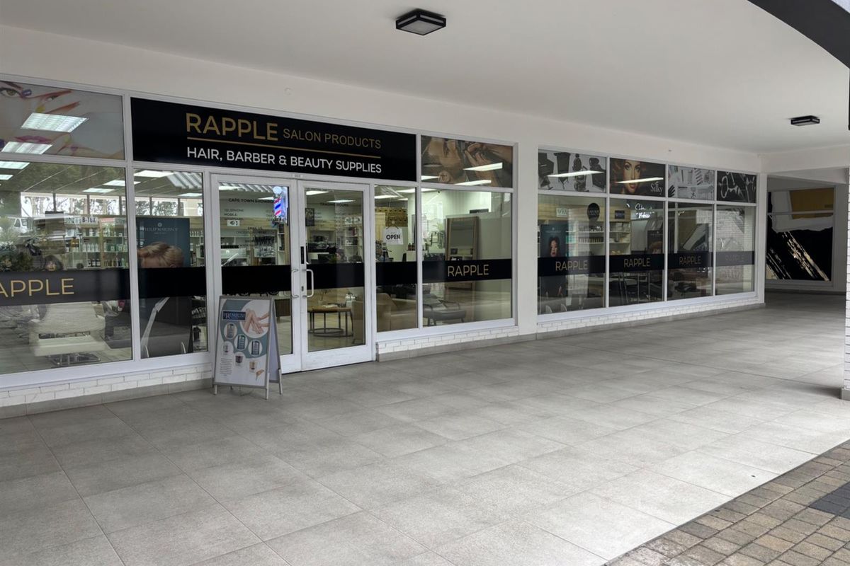 Commercial storefront featuring a large glass facade with branded signage, tiled walkway, and recessed lighting, suitable for retail or salon operations.