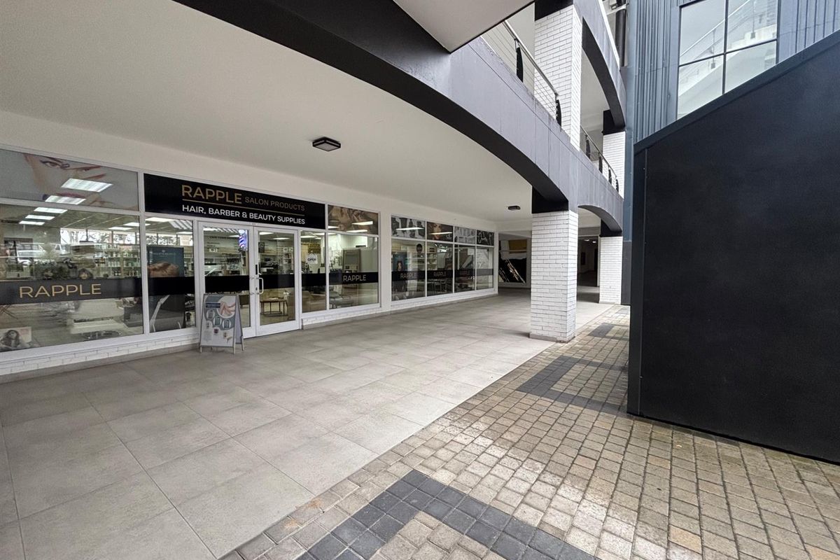 Commercial storefront entrance featuring a covered tiled walkway, glass facade, and modern brick architectural detailing in a well-maintained retail complex.