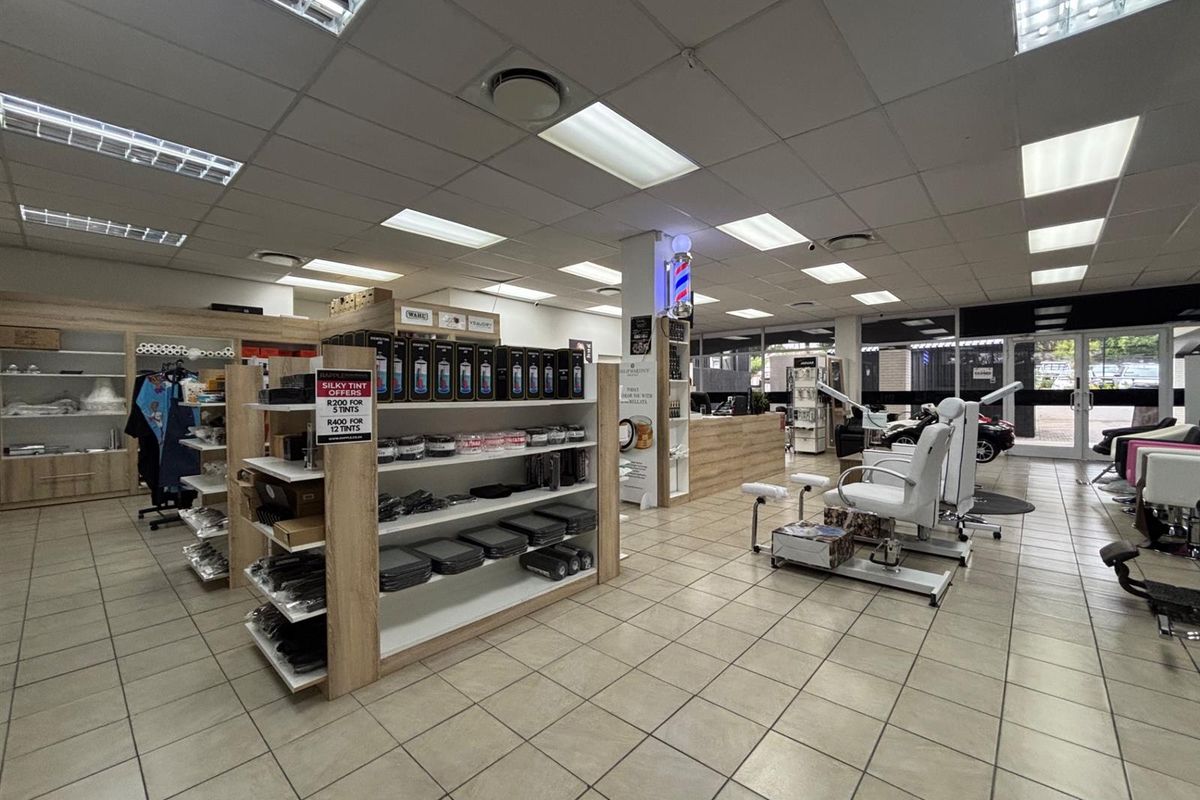 A well-maintained commercial salon space featuring tiled flooring, suspended ceilings with recessed lighting, built-in shelving, and a reception area.