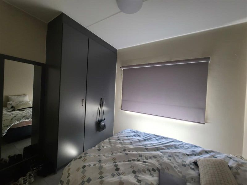 A bedroom featuring a dark built-in wardrobe and a fitted roller blind.